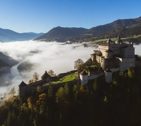 Hohenwerfen Castle on a mountain surrounded by mist and alpine valley view